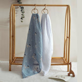 Dalmatian print swaddle and white blanket hanging side by side on rack